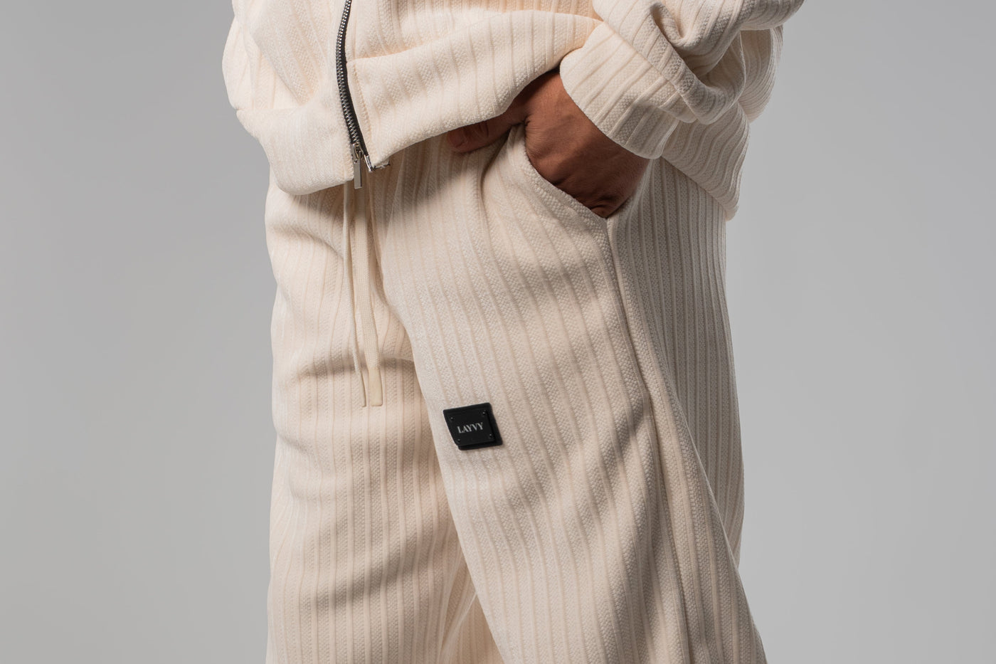 Beige ribbed knit pants worn by a person on a gray background